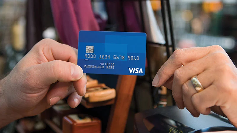 A happy person using a Visa card while shopping abroad
